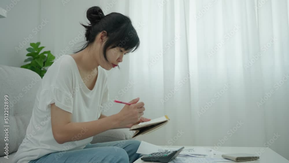 Asia woman is reading the details of the payment date and writing the appointment date on the calendar. Women are having financial problems due to mismanagement of money. concept financial Asia woman is reading the details of the payment date and writing the appointment date on the calendar. Women are having financial problems due to mismanagement of money. concept financial