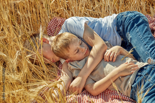 Two children are sleeping in a field of wheat. Brothers relaxing outdoors