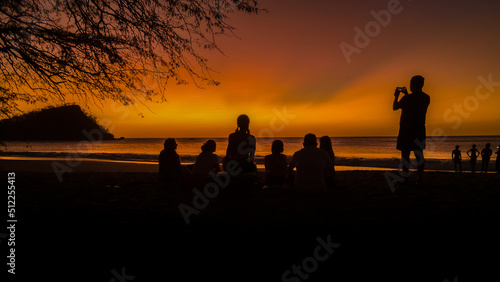 View of a magical sunset on the beach with silhouette of peolple enjoying in the beach of Costa Rica