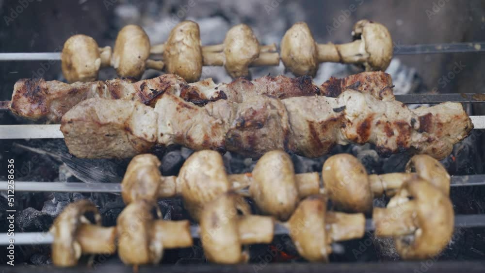 Cooking on an open fire. Barbecue and champignons are cooked on a brazier with coals. The man blows the coals. Cooking on an open fire. Barbecue and champignons are cooked on a brazier with coals. The man blows the coals.