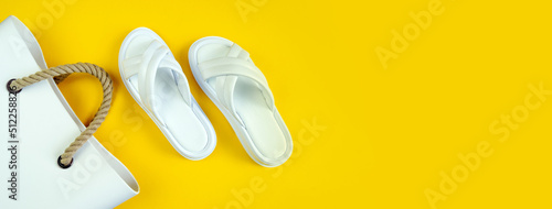 Women's summer white slippers and a white rubber bag with brown handles on a yellow background. Slippers. Banner for insertion into site. Place for text cope space. Horizontal image photo