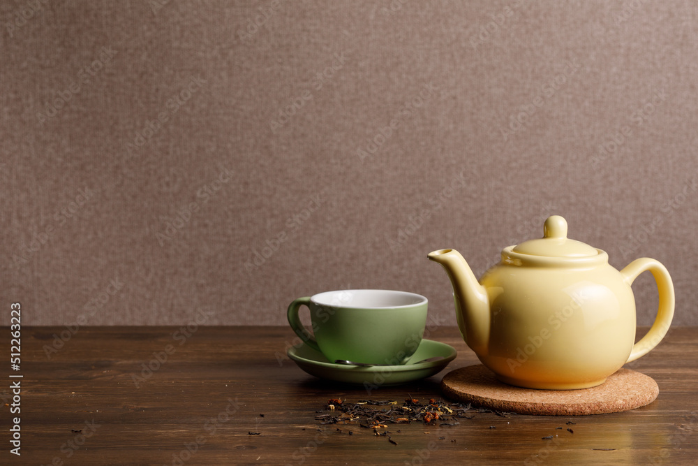 Teapot with cup on wooden background. Copy space