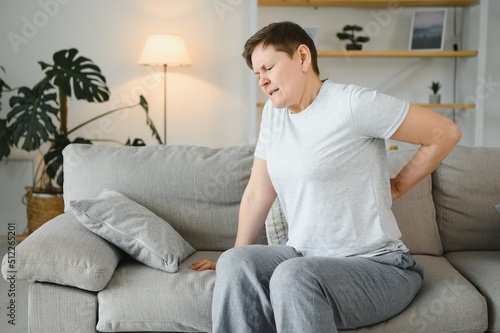 Senior adult woman touching back feeling backache, discomfort low lumbar muscular kidney pain. Elderly woman felt back pain after exercising, fitness exercises caused health problems in retirement.