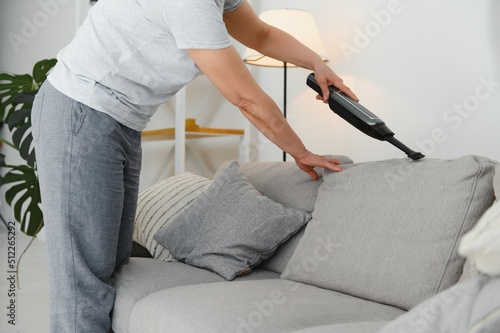 Portrait of senior woman with vacuum cleaner indoors at home, hoovering