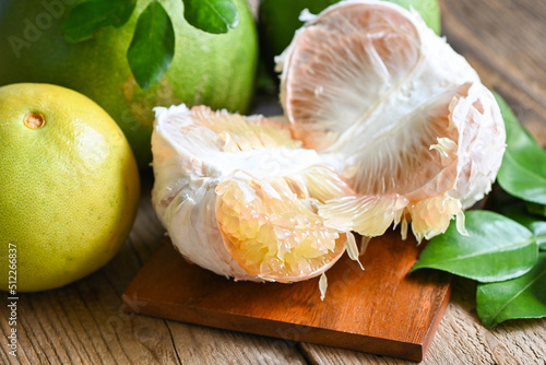 Fresh green pomelo peeled and leaf frome pomelo tree , pomelo fruit on wooden plate  background, pummelo , grapefruit in summer tropical fruit  in thailand photo