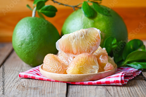pomelo fruit on wooden plate  background, fresh green pomelo peeled and leaf frome pomelo tree , pummelo , grapefruit in summer tropical fruit  in thailand photo