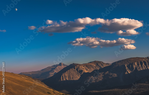 Vertical view of bare mountain peaks about tree line as seen from trail ridge road in Rocky Mountain National Park  Colorado  at sunset  blue sky with beautiful clouds and rising moon in background