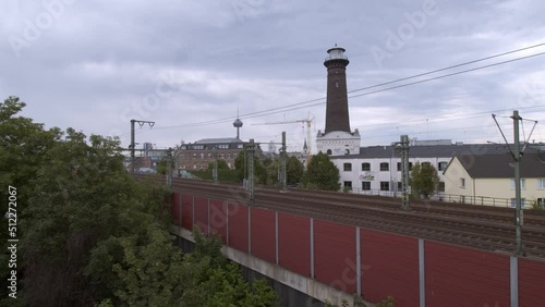 A commuter train on the way to Aachen in Cologne Ehrenfeld on a cloudy day in front of the panorama scenery of Cologne Ehrenfeld with the TV tower in the background. Shot in 4K in summer 2019 photo