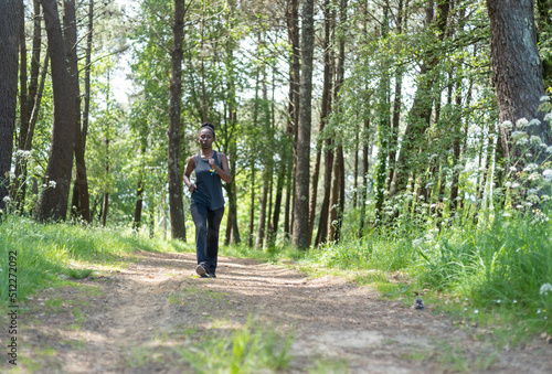 Young sports woman running in the woods on a sunny day