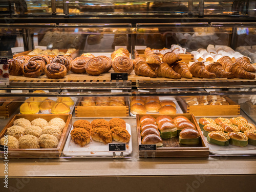 Assorted pastry and bread arranged on tray selling at bakery shop.