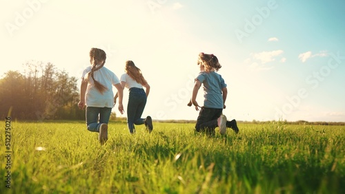 kids run in the park. a large group of a team of children running back view sunlight in the summer on the grass in the park camera movement. lifestyle people in the park happy family kid dream concept