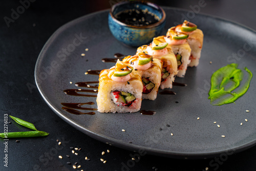 Traditional Asian rolls and sushi with soy sauce and wasabi served on a dark background