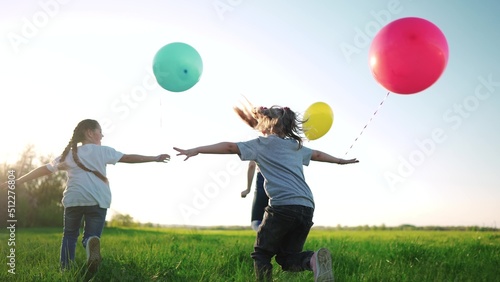 children with balloons a run in the park. happy family kid dream concept holiday. a group of children run in the summer on the grass in the park hold balloons at a birthday party play. kids sun run