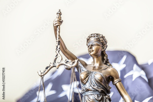 Bronze figurine of Themis holds wedding rings on scales of balance, being in foreground. Couple divorce.