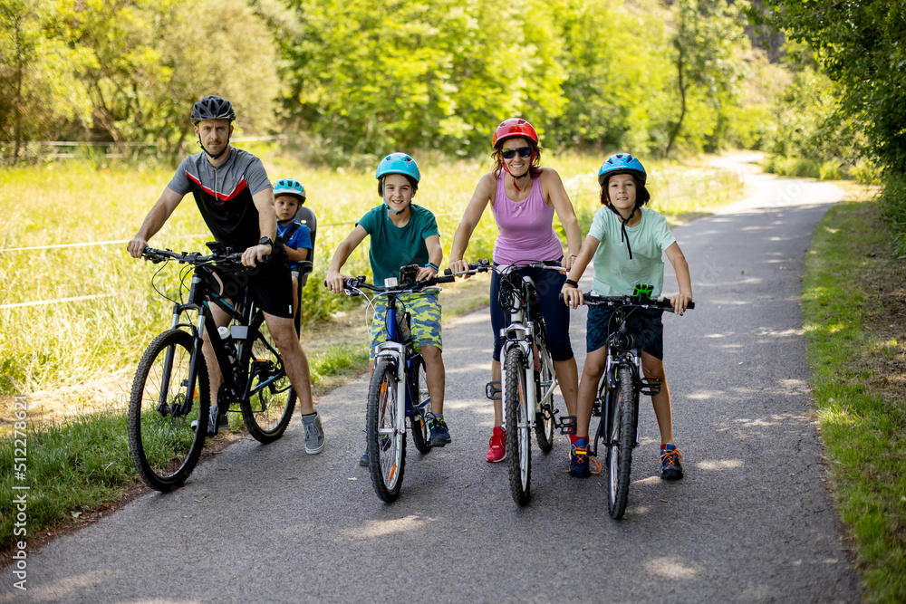 Happy family, parents and children, riding bikes in the park on a sunny summer day, enjoying quality family time