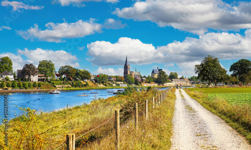 Beautiful dutch rural countryside landscape, riverside waterfront bike cycle path to ferry station, medieval town church tower, river Maas - View from Beesel on Kessel, Netherlands, Limburg photo