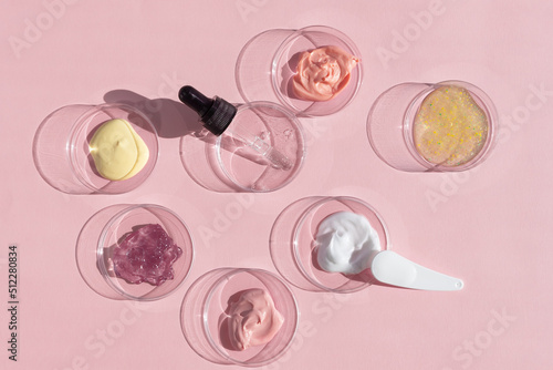 Multicolored texture of cream, scrub and gel with a pipette in a Petri dish on a pink background. The concept of laboratory research of cosmetics. Smears of cosmetic skin care products