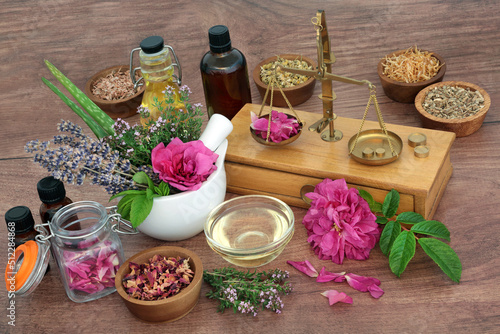 Natural remedy to treat eczema, acne and psoriasis. Preparation of herbal plant based medicine for skincare concept with old brass scales, herbs, flowers, essential oil bottles. On rustic wood.