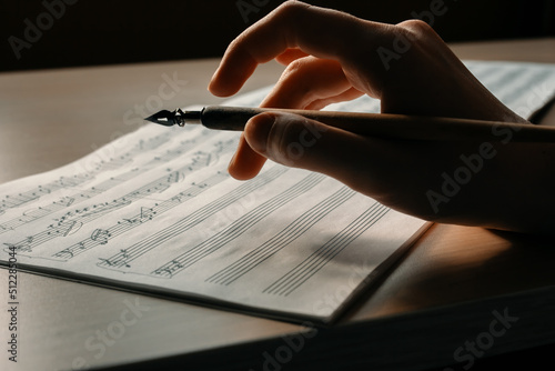 Canvastavla Woman's hand with a pen drawing notes in a music book, writing a melody by hand,