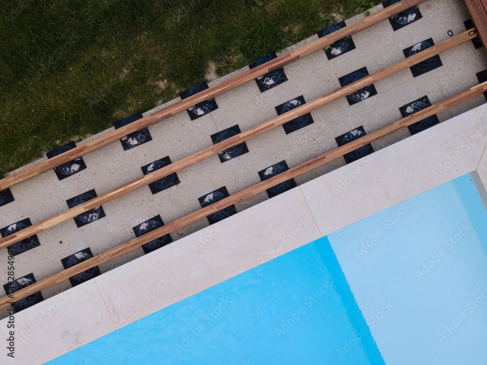 Drone flight over beautiful green garden with pool and the wooden terrace of the pool is currently in progress