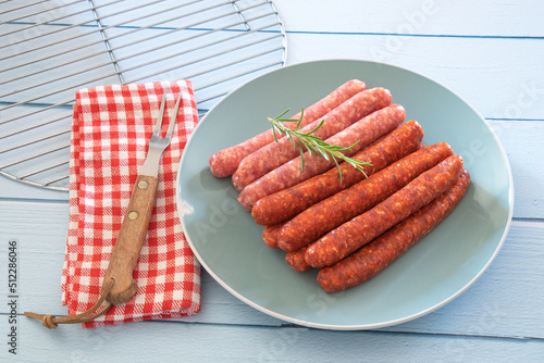 saucisses et merguez crues dans une assiette sur une table 