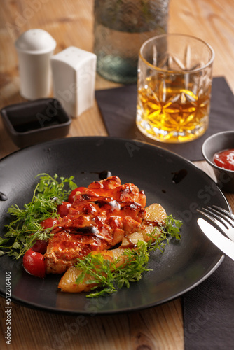 culinary dish chicken steak. restaurant serving. black tableware  wooden table