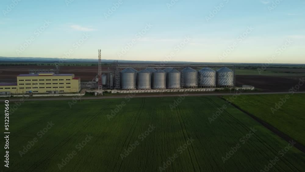 Grain elevator. Metal grain elevator in agricultural zone. Agriculture storage for harvest. Grain silos on green nature background. Exterior of agricultural factory. Nobody. Grain elevator. Metal grain elevator in agricultural zone. Agriculture storage for harvest. Grain silos on green nature background. Exterior of agricultural factory. Nobody.