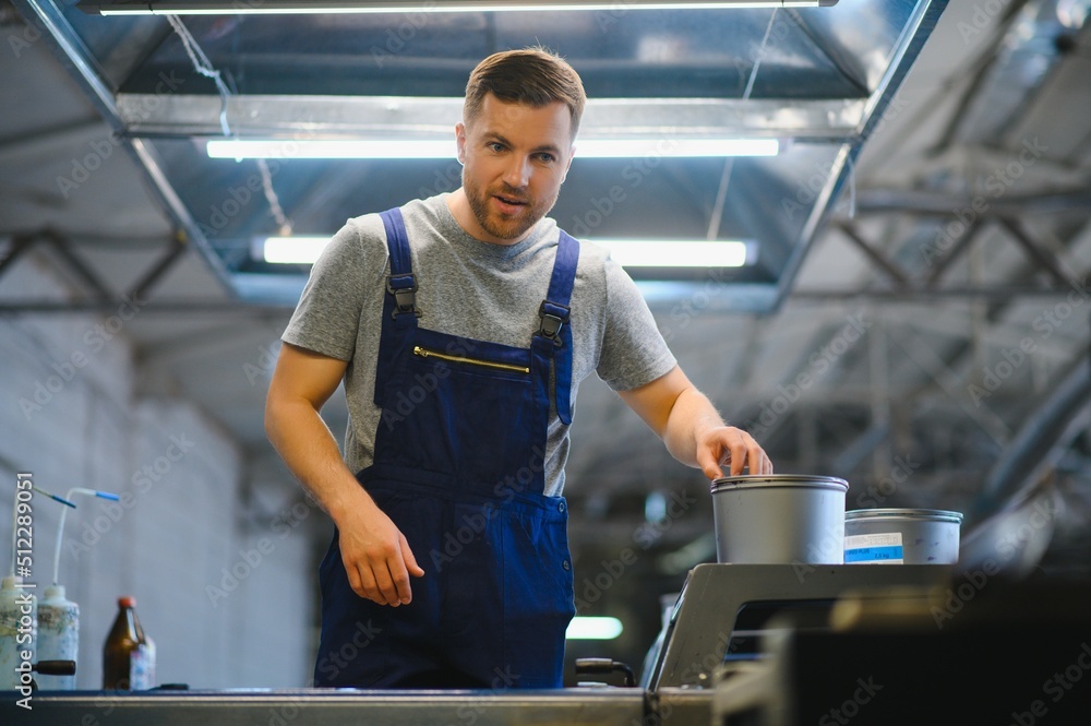 Man working in printing house with paper and paints Man working in printing house with paper and paints