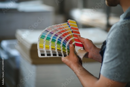 Man working in printing house with paper and paints