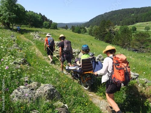 Randonnée en montagne solidaire avec handicapé en joelette fauteuil roulant de randonnée sur les sentiers avec des gens et personne en handicap