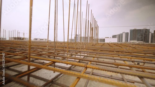 Iron reinforcement is basis for pouring foundation of house with concrete slab. Construction design, engineering communications. Top floor or roof of building under construction with view of city. photo