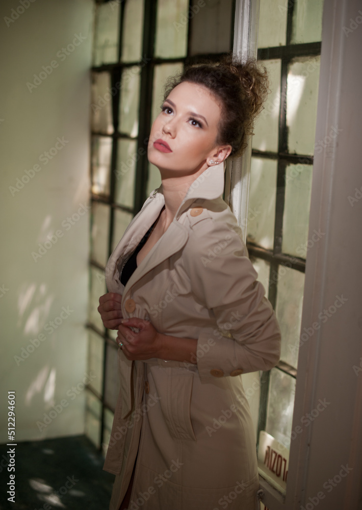 lovely sexy woman at the window .young girl in coat posing in front of camera. Fashion woman in coat. Slim young fashion model wearing white coat. portrait of young beautiful fashionable woman 