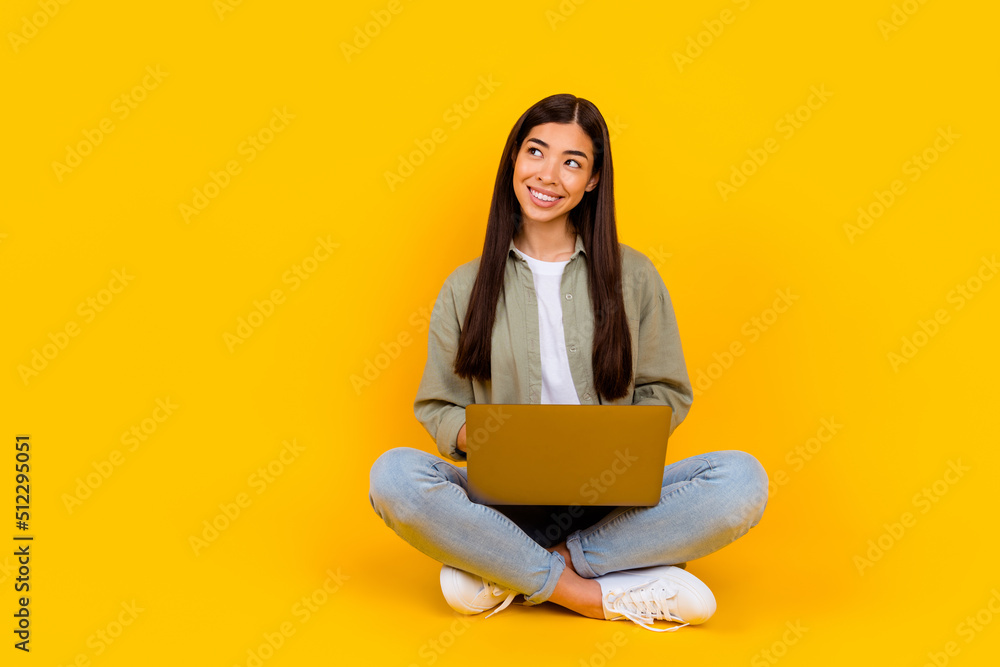 Full size portrait of cheerful pretty girl use netbook look interested empty space isolated on yellow color background Full size portrait of cheerful pretty girl use netbook look interested empty space isolated on yellow color background