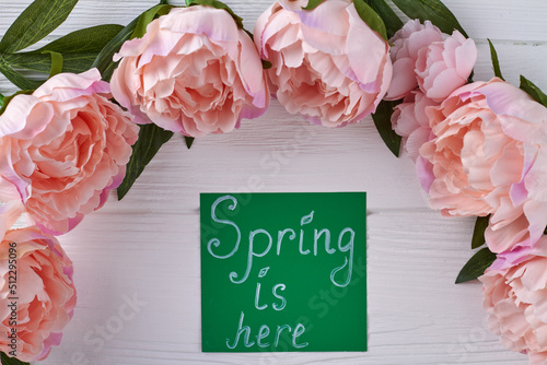 Peony flowers frame on white wooden desk. Spring is here concept. photo