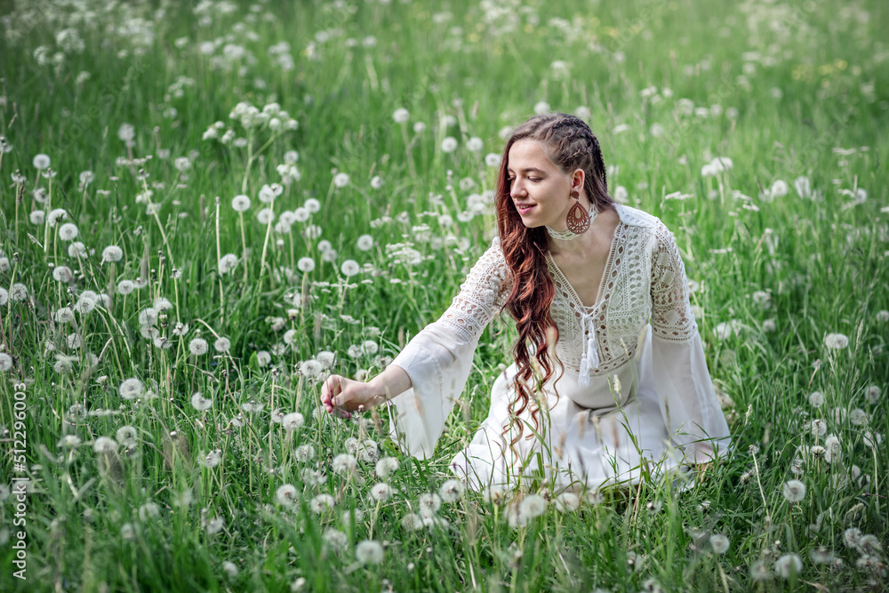 Beautiful young woman in green grass among white fluffy dandelions. A happy smiling girl in a white dress sits on a spring lawn. Healthy life without allergies Beautiful young woman in green grass among white fluffy dandelions. A happy smiling girl in a white dress sits on a spring lawn. Healthy life without allergies