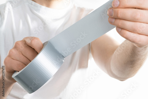 Close up image of mand holding adhesive tape on white background trying to fix something