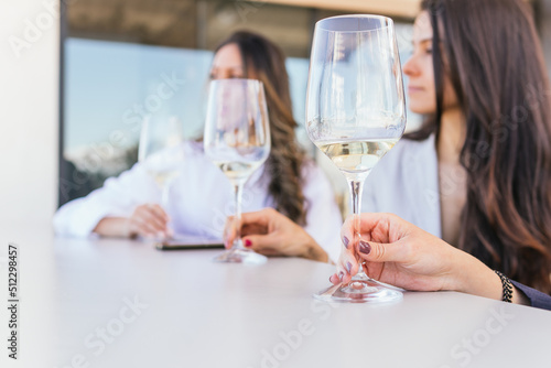 Anonymous hispanic women with wine sitting at restaurant table photo