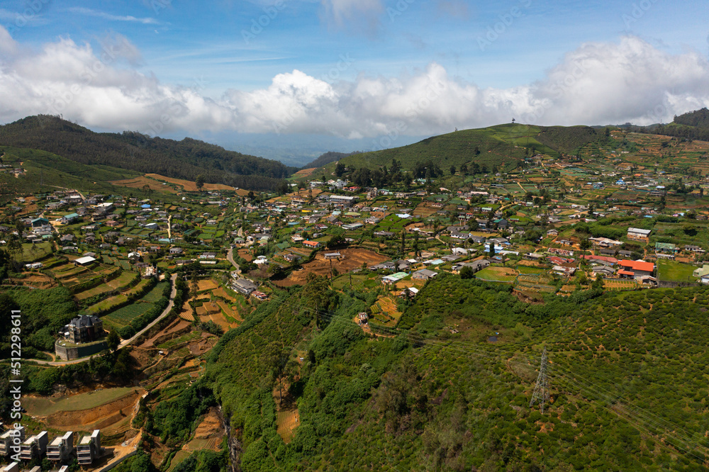 Aerial view of Houses among tea plantations on the slopes of the mountains. Nuwara Eliya, Sri Lanka. Tea estate landscape.