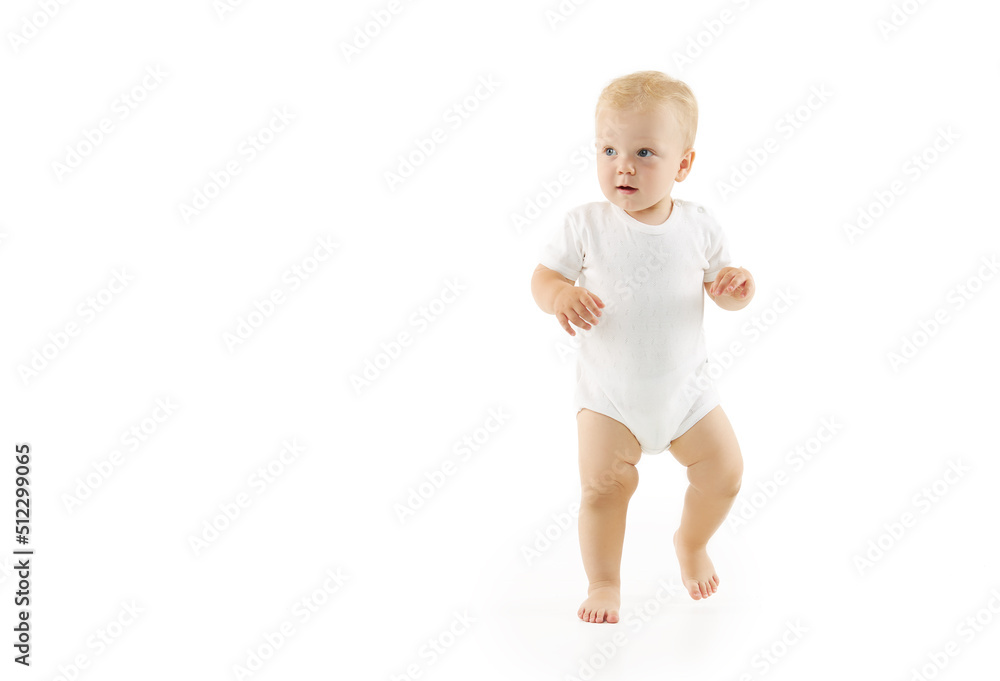 Cute baby learns to walk on a white isolated background. Happy smiling child in white clothes makes first confident steps Cute baby learns to walk on a white isolated background. Happy smiling child in white clothes makes first confident steps