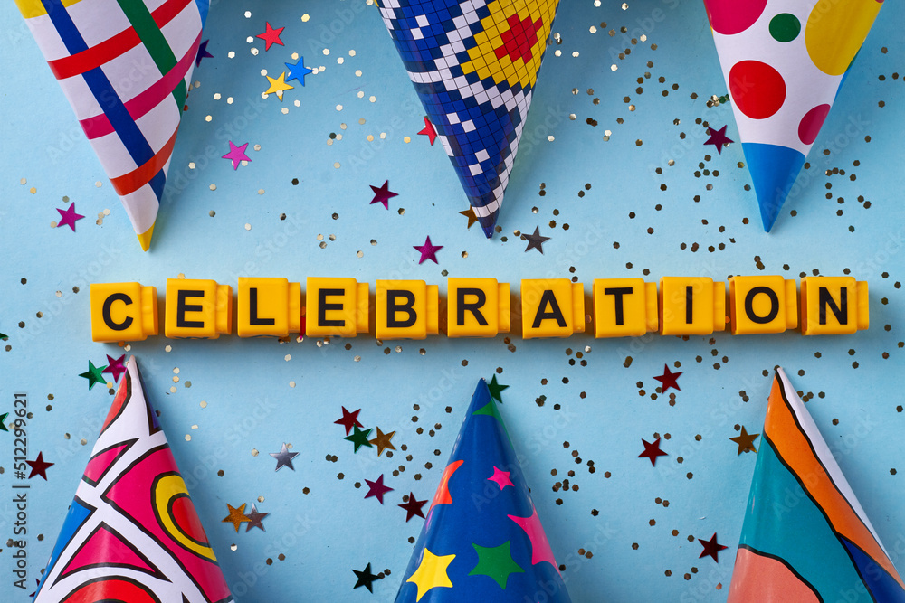 Obraz premium Flat lay celebration word and birthday cones with confetti. Isolated on blue background.
