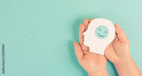 Holding a head with a smiling face in the hands, mental health concept, positive mindset, support and evaluation symbol photo