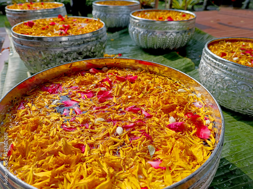 Flower water filled with colorful flowers is held in a container for hand watering to the elderly. The concept of traditional Songkran traditions of Thailand.