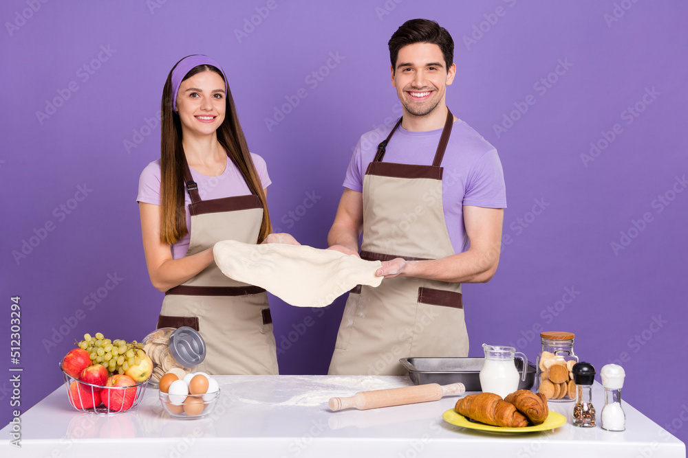 Portrait of cheerful satisfied people hold pizza dough look camera isolated on purple color background Portrait of cheerful satisfied people hold pizza dough look camera isolated on purple color background