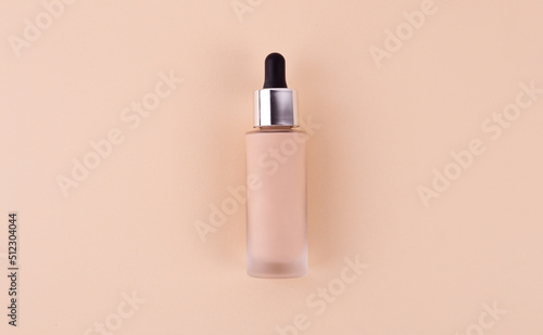 Liquid foundation cream unbranded bottle on a beige background. BB cream for professional make-up, eyedropper for applying to the face. Cosmetic female accessory, fluid. Mock up concept