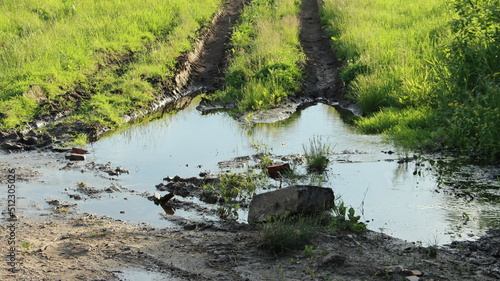 Large puddle on a field road with a deep rut