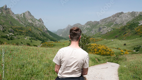 Hombre blanco de ruta en caballo por valle verde entre montañas rocosas photo