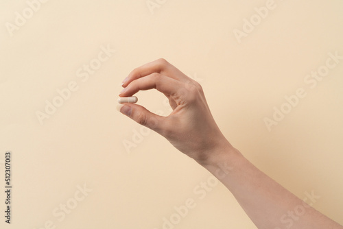 a female hand holding a single pill