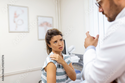 Woman having a shoulder pain. Doctor working in the office and listening to the patient, she is explaining her symptoms, healtcare and assistance concept
