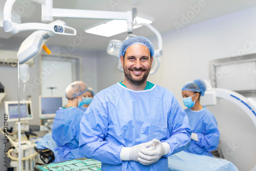 Portrait of male surgeon in operation theater looking at camera. Doctor in scrubs and medical mask in modern hospital operating theater.