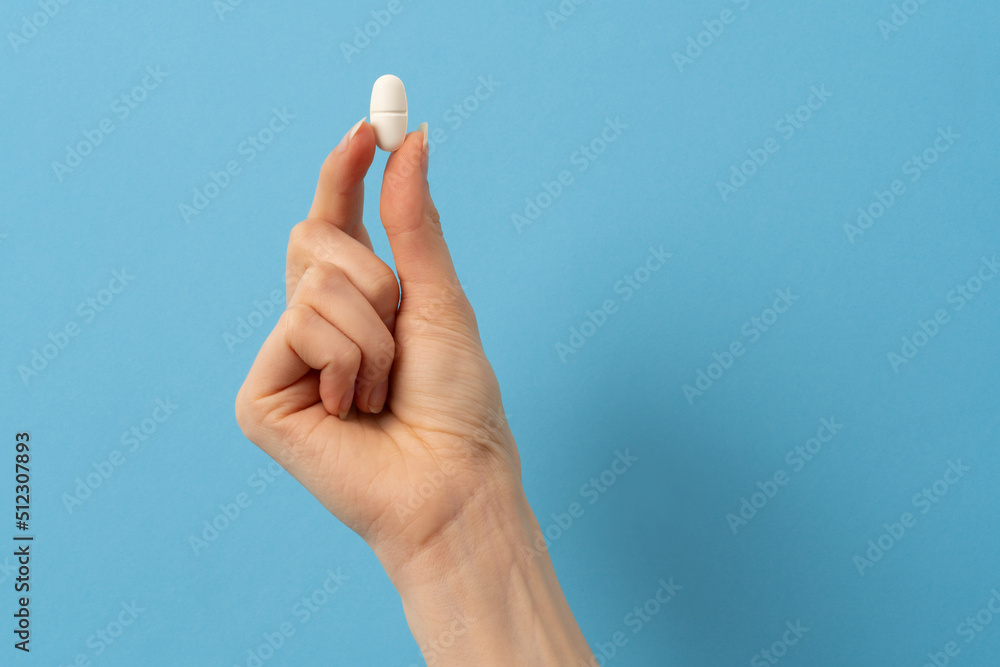 a female hand holding a single pill a female hand holding a single pill